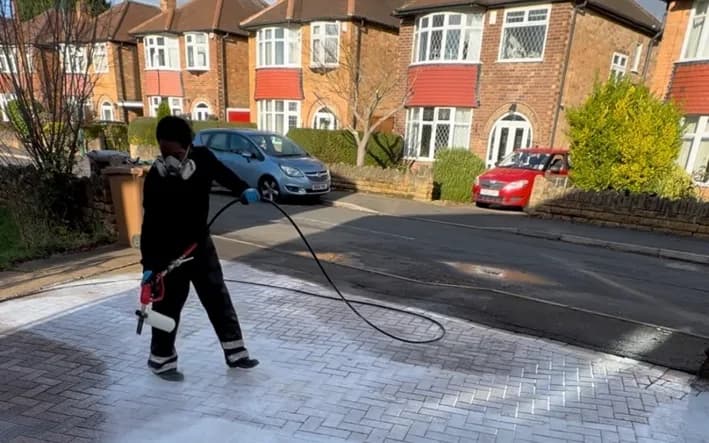 JetMagic technician soft washing a driveway in Nottingham, applying a low pressure biocide treatment