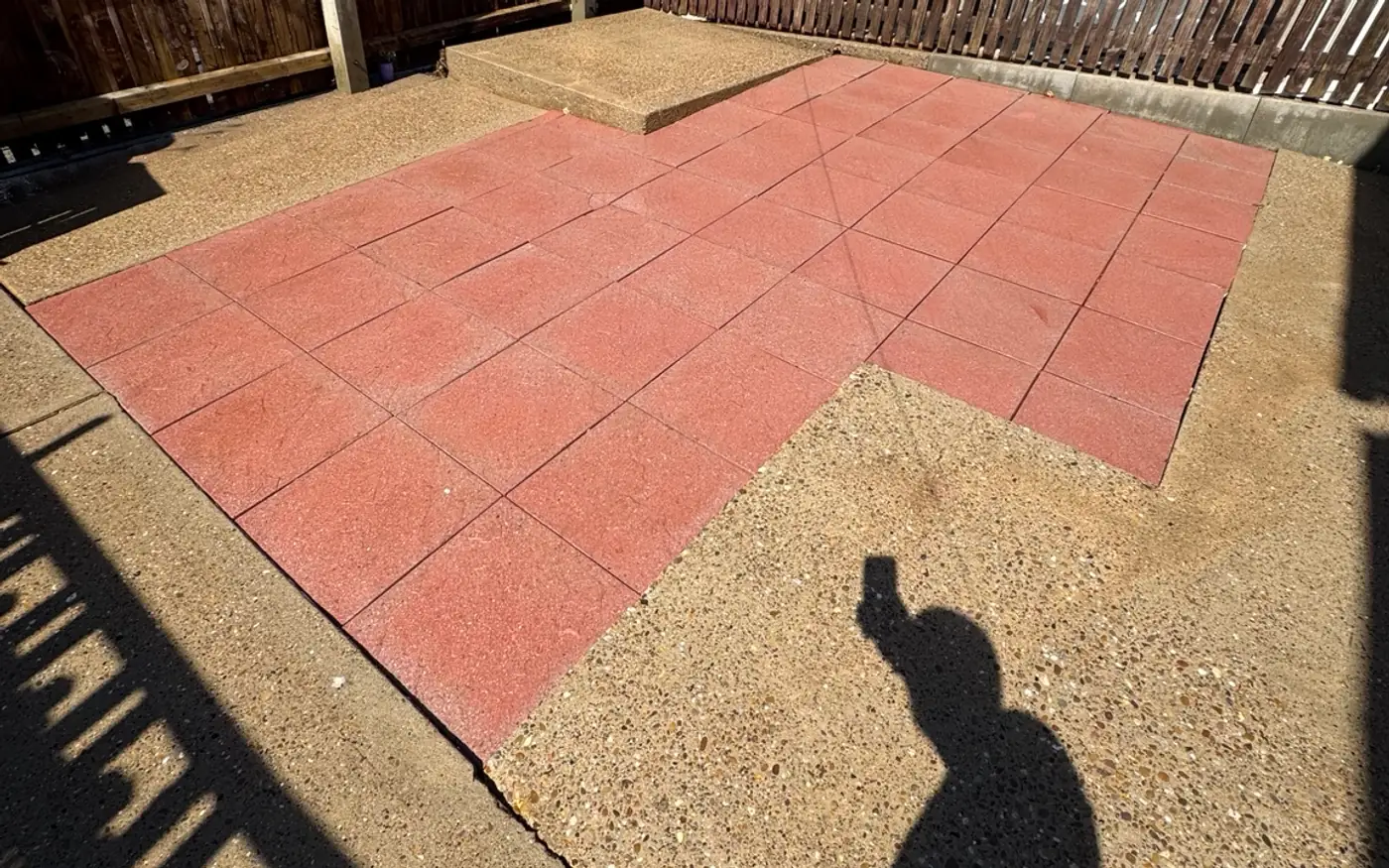 The same patio cleared of weeds and moss after soft washing, slabs back to a clean red finish